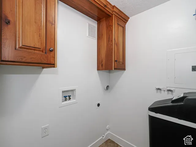 Private in-unit laundry room featuring matching knotty alder cabinetry with crown molding and full-size washer and dryer hookups