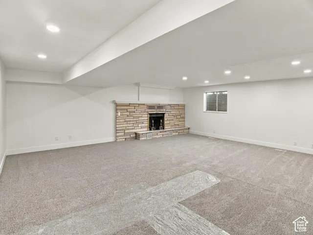 Expansive interior space featuring a stone fireplace surround, recessed ceiling lighting, and neutral carpeting