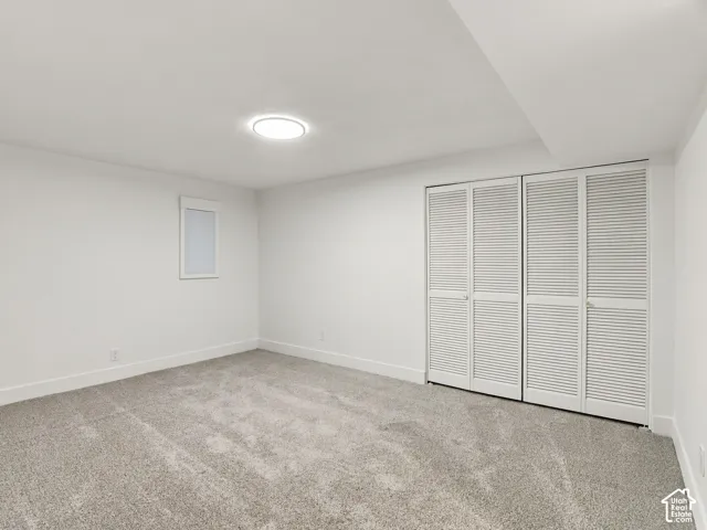 Neutral-toned wall-to-wall carpeting, dual floor-to-ceiling closets with louvered doors, and a flush-mount circular ceiling light