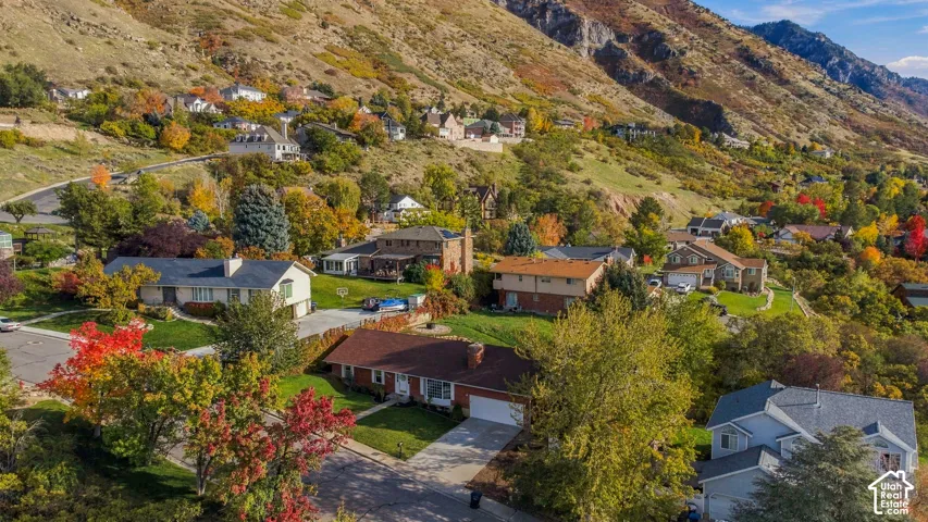 Aerial perspective featuring an established neighborhood situated against a prominent mountain backdrop with mature trees and seasonal foliage