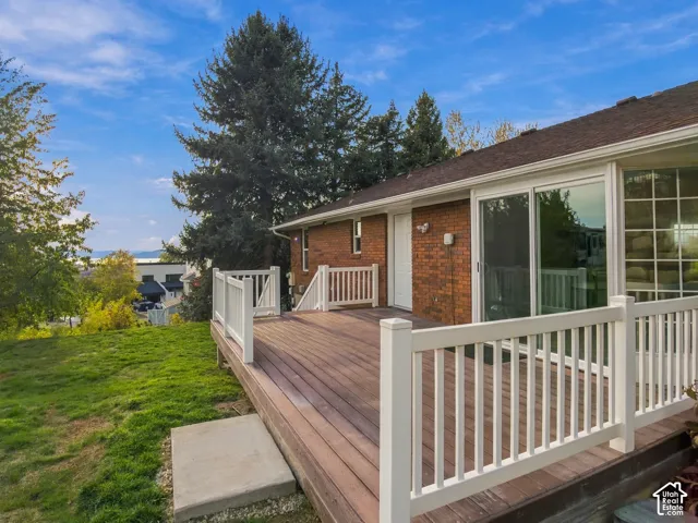 Raised deck with white vinyl railing, brick exterior, sliding glass doors, and grass yard