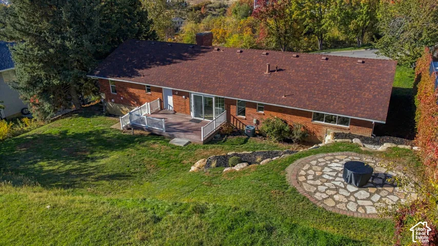 Brick exterior residence featuring an elevated wood deck with white railings, a circular flagstone patio, and mature landscaping