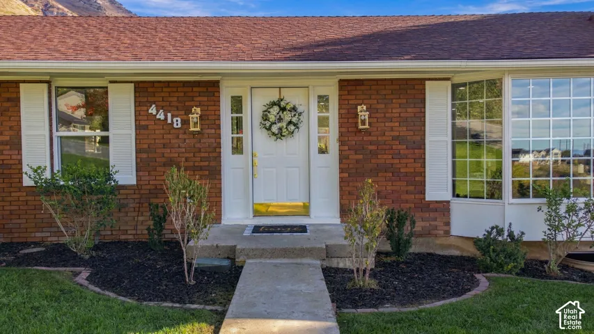 Brick exterior featuring white shutters, a multi-pane bay window, and a central entry door with sidelights