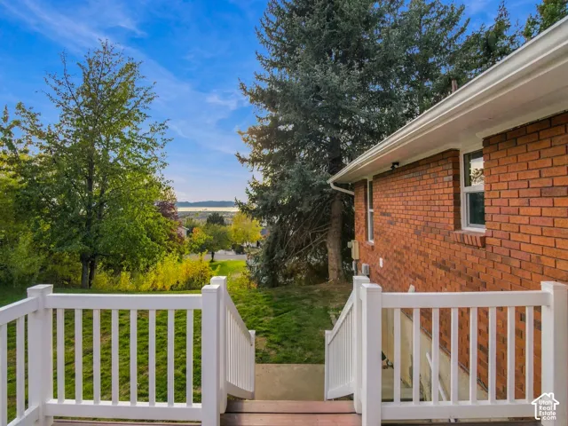 Exterior red brick siding, white vinyl railing, and mature landscaping