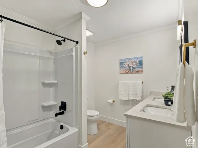 Bathroom featuring a dual-sink vanity with a stone-composite countertop, wood-finish flooring, and matte black plumbing fixtures