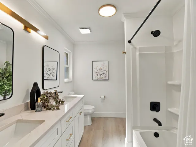 Dual-sink vanity with light-toned stone countertop, matte black fixtures, integrated medicine cabinet mirrors, and wood-finish flooring