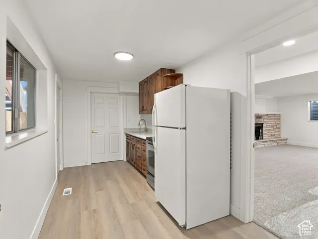 Kitchenette featuring wood-finish cabinetry, solid surface countertops, stainless steel appliances, and wood-finish flooring