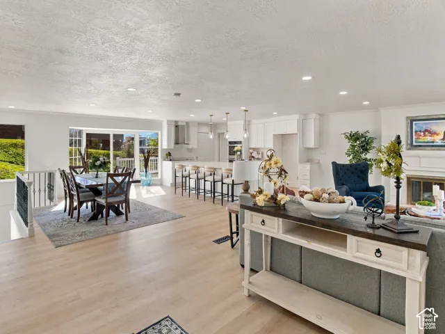 Open-concept living space featuring wood-finish flooring, recessed lighting, kitchen island with bar seating, and a fireplace with a mantel
