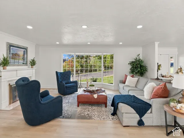 Large bay window, fireplace with a decorative mantel, recessed lighting, and wood-finish flooring
