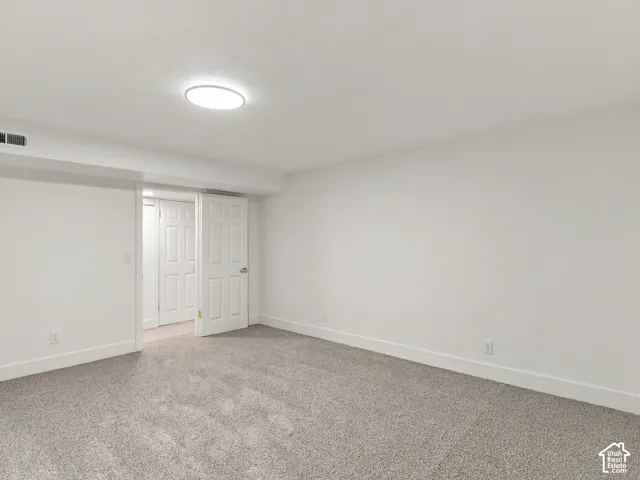 Neutral-toned wall-to-wall carpeting, crisp white walls, and a recessed ceiling light fixture, featuring interior panel doors