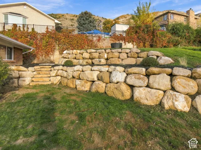 Tiered boulder retaining walls with integrated natural stone steps and landscaped slope