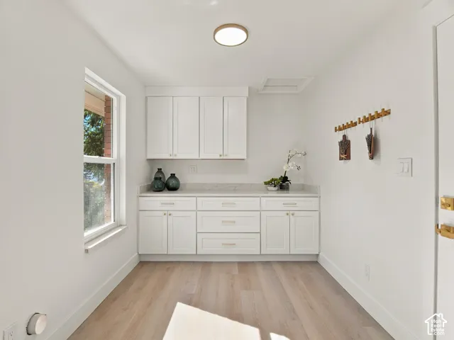 Built-in cabinetry featuring white shaker-style doors, stone-composite countertop, wood-finish flooring, and recessed ceiling lighting