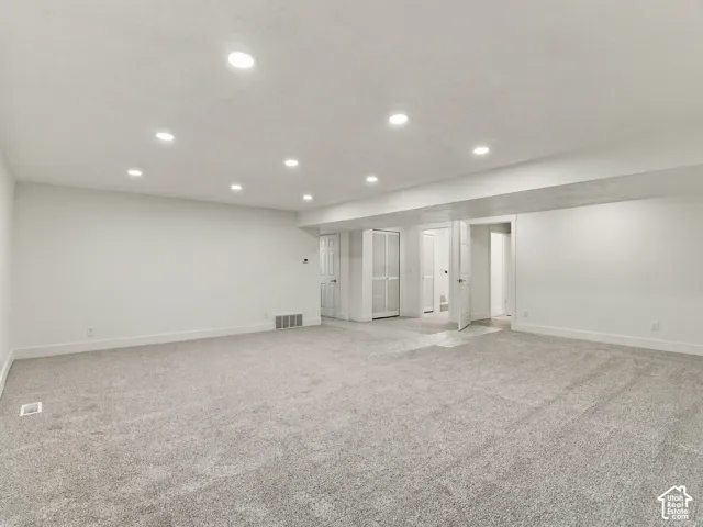 Neutral-toned carpeting, recessed ceiling lighting, and multiple interior doorways featuring panelled doors