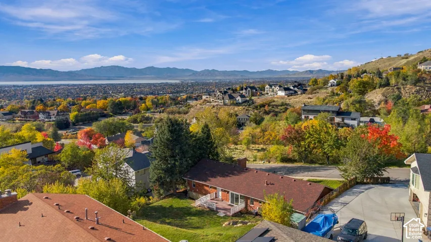 Elevated residential lot featuring a multi-level deck, concrete driveway, and expansive mountain and valley horizon