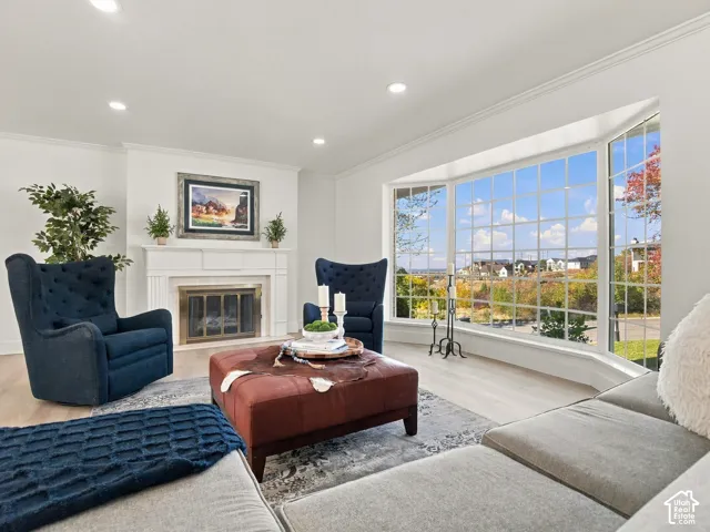 Expansive living area featuring a large bay window, fireplace with a custom mantel, recessed lighting, and wood-finish flooring