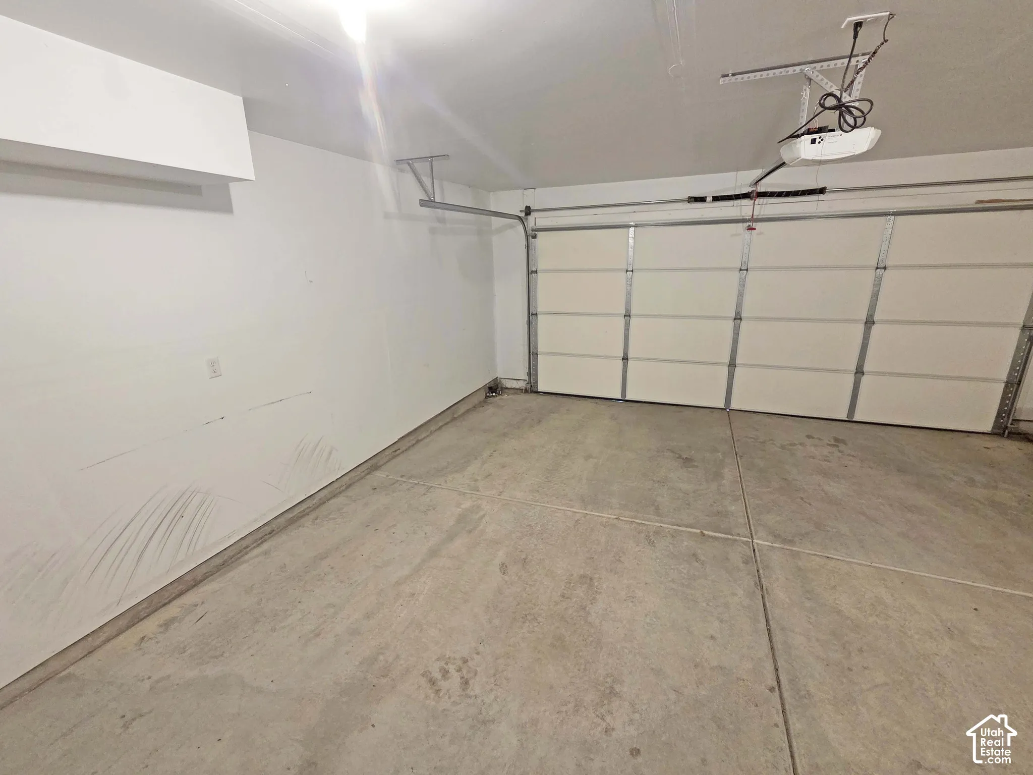 Garage interior featuring a concrete floor, finished walls, and an automated overhead door mechanism