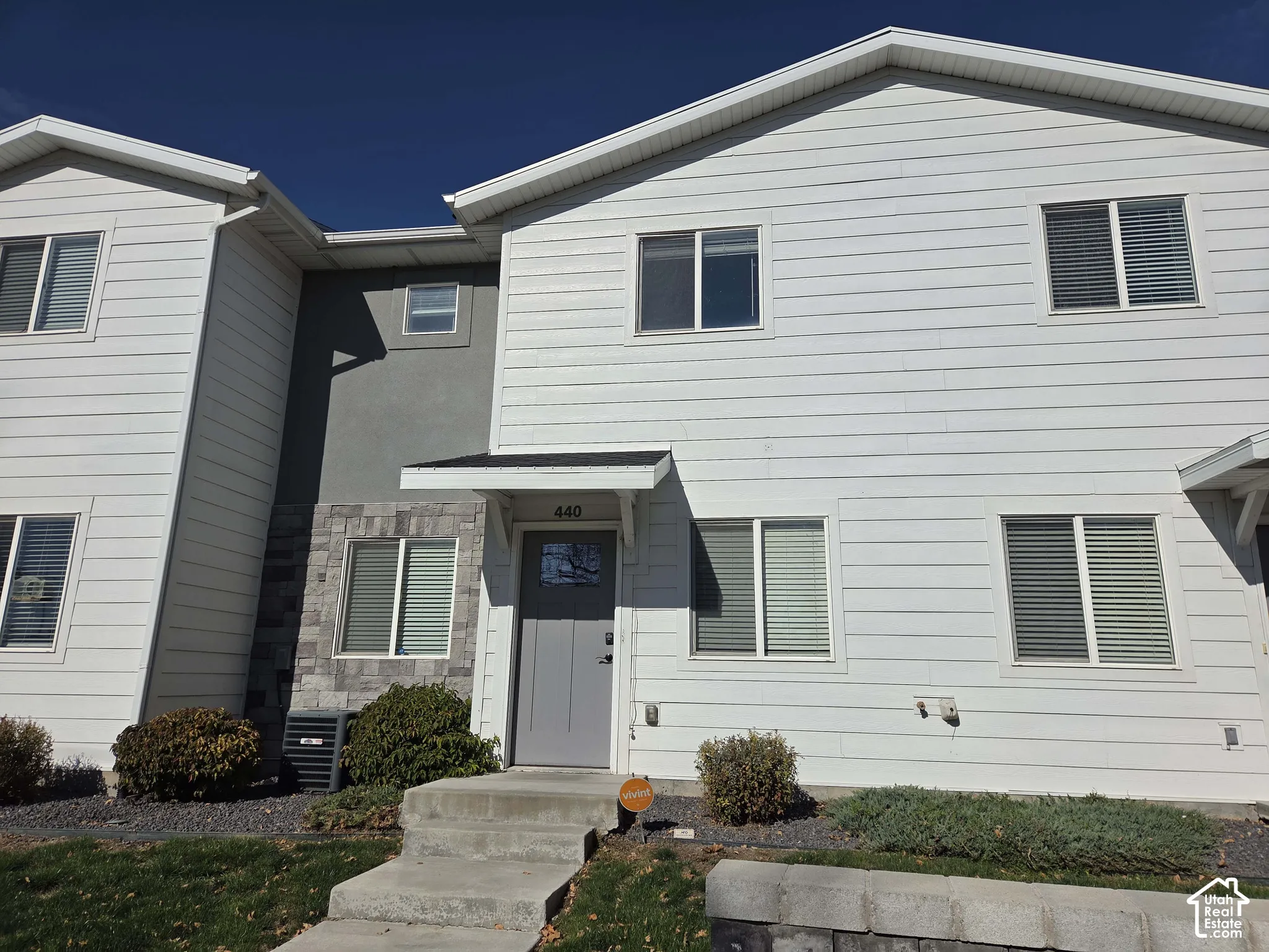 Exterior facade featuring horizontal siding, stone veneer accents, gray panel-style front door, and a covered entryway