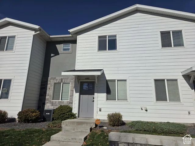 Exterior facade featuring horizontal siding, stone veneer accents, gray panel-style front door, and a covered entryway