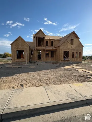 Two-story residential structure under construction featuring a multifaceted roofline, gabled roof peaks, and an expansive structural wood frame
