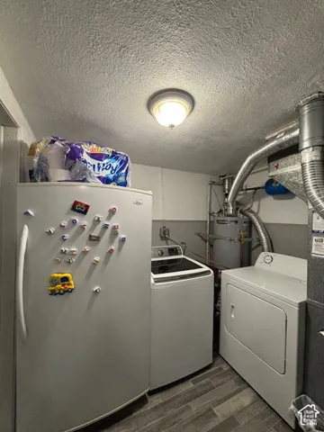 Utility area featuring wood-finish flooring, ceiling-mounted lighting, and integrated mechanical components including a water heater and furnace venting