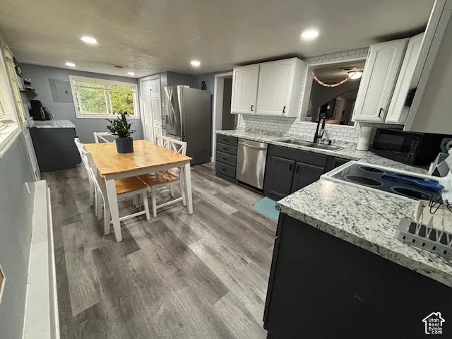 Kitchen featuring two-tone cabinetry, stone-finish countertops, subway tile backsplash, recessed lighting, and wood-finish flooring