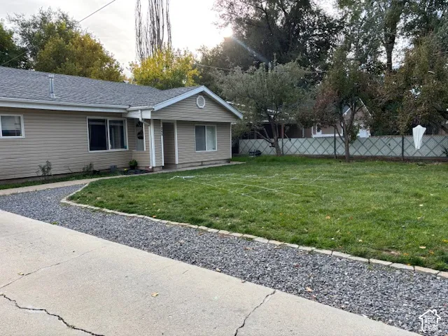 Siding-clad exterior featuring a gravel driveway border, concrete approach, and open lawn area