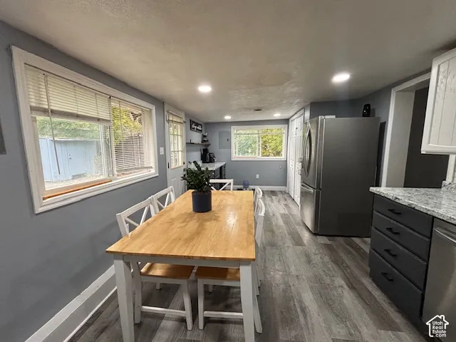 Kitchen featuring wood-finish flooring, recessed lighting, stainless steel refrigerator, grey cabinetry, and stone-finish countertops