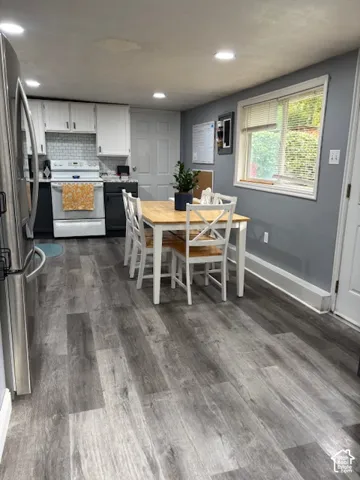 Kitchen featuring wood-finish flooring, recessed lighting, dual-tone cabinetry, and a subway tile backsplash