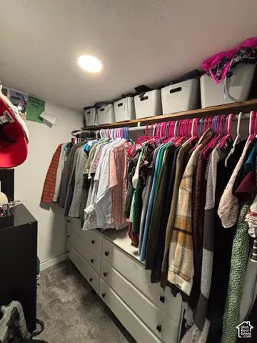 Walk-in closet featuring built-in cabinetry with six integrated drawers, recessed lighting, and a continuous wood-finished upper shelf