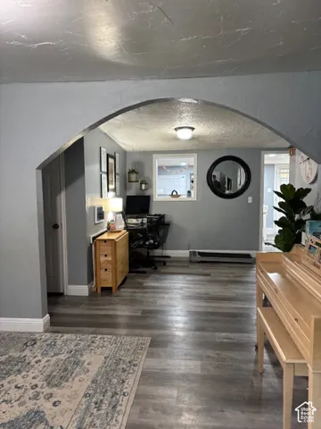 Interior space featuring a prominent arched doorway, wood-finish flooring, and a recessed window