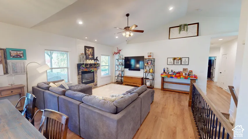 Vaulted ceilings, wood-finish flooring, stone-surround fireplace, and wrought-iron stair railing