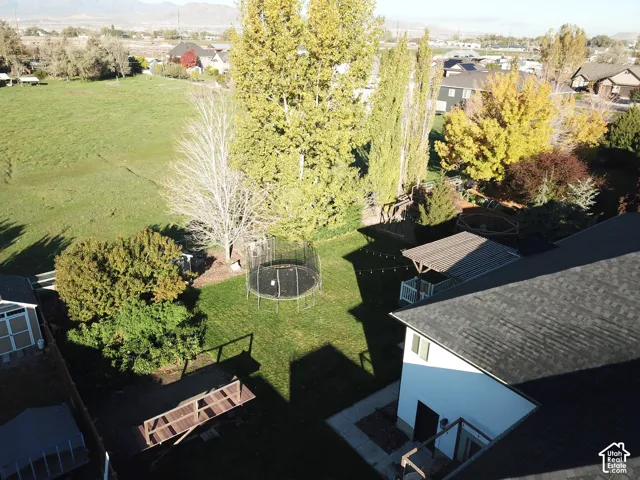 Expansive backyard featuring a mature treed landscape, a covered wooden pergola, a lawn area, and a detached storage structure