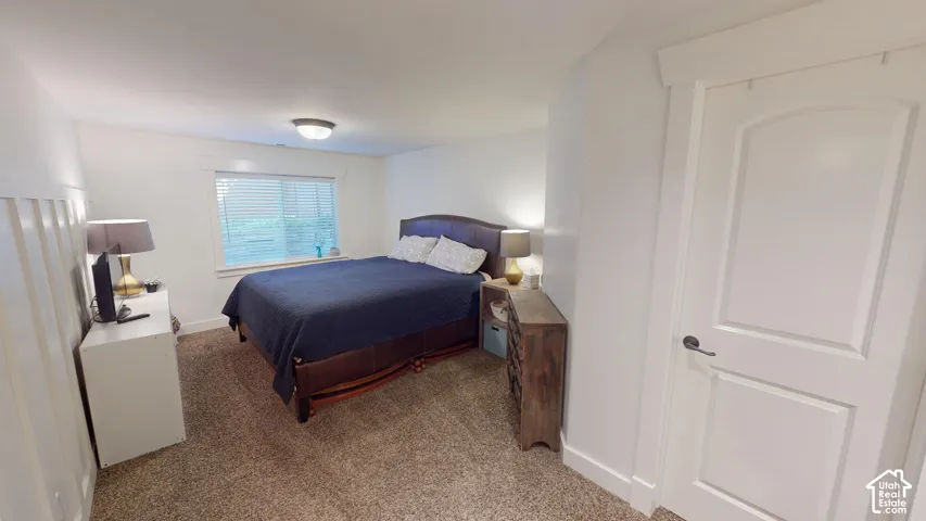 Room featuring neutral carpeting, wainscoting, a multi-panel interior door, and a flush-mount light fixture