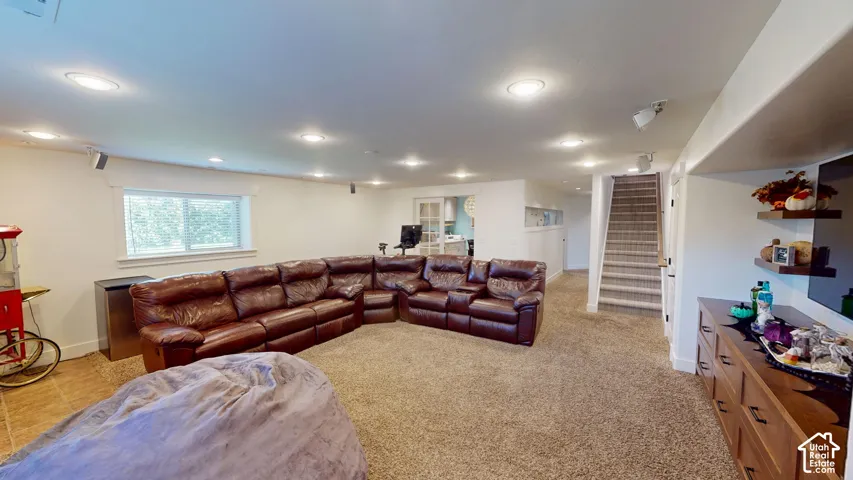 Recessed lighting, wall-to-wall carpeting, built-in wooden shelving, and a carpeted staircase with a handrail
