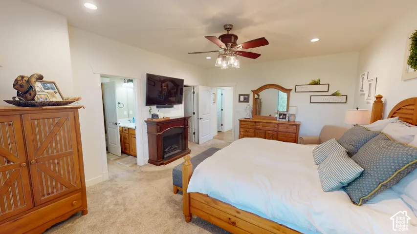 Bedroom featuring a built-in fireplace with a mantel, recessed ceiling lighting, a ceiling fan with light fixture, and neutral carpeting