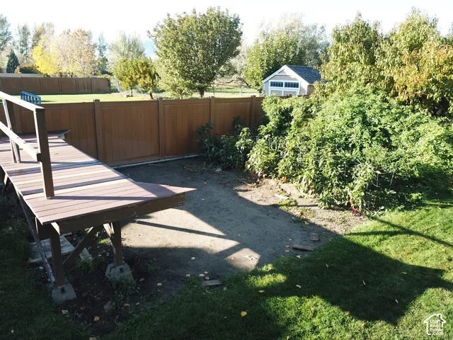 Backyard featuring a raised composite deck, solid-panel privacy fencing, mature trees, and a detached outbuilding