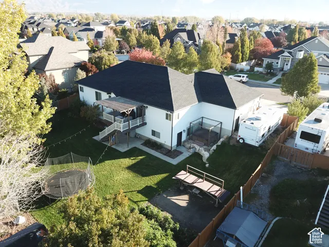 Rear exterior featuring a covered elevated deck, concrete patio area, built-in ground-level spa, and fenced yard with mature trees