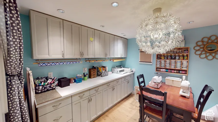 Built-in cabinetry with shaker-style doors, expansive countertop surface, recessed lighting, and a decorative statement pendant light
