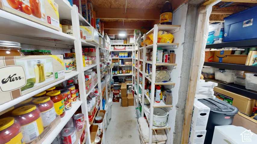 Dedicated storage space featuring floor-to-ceiling white painted wood shelving and exposed ceiling joists