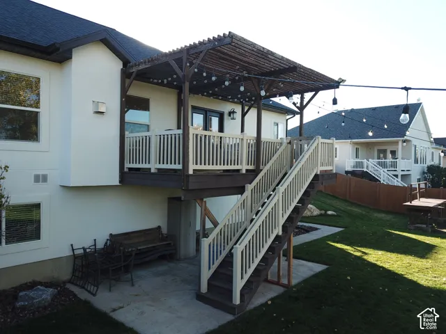 Elevated deck featuring a wood pergola, vinyl railings, and a staircase leading to a concrete patio