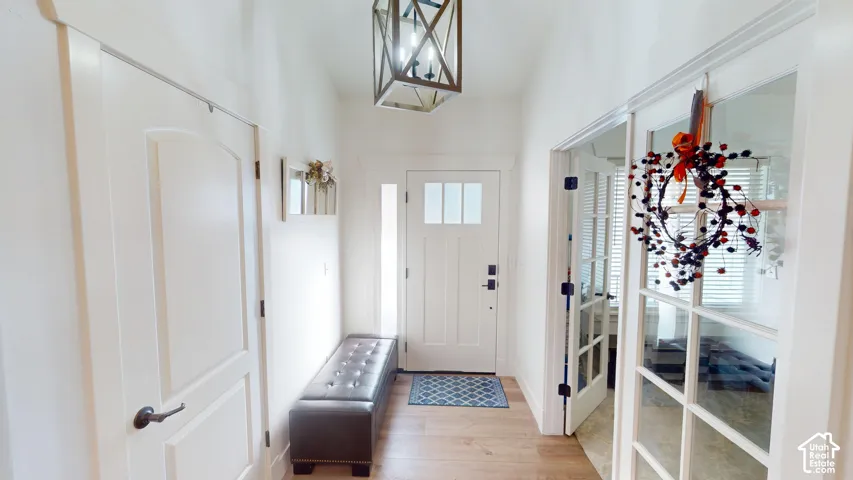 Entryway featuring a Craftsman-style front door with glass transom panels, wood-finish flooring, a geometric lantern-style pendant light, and double glass-paneled interior doors