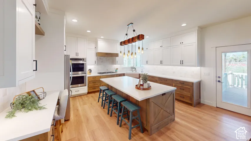 Kitchen featuring shaker-style cabinetry, a central island with countertop seating, stone-finish backsplash, built-in double oven, and wood-finish flooring