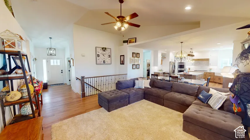 Vaulted ceilings featuring a recessed ceiling fan, wood-finish flooring, and a metal-spindle staircase railing