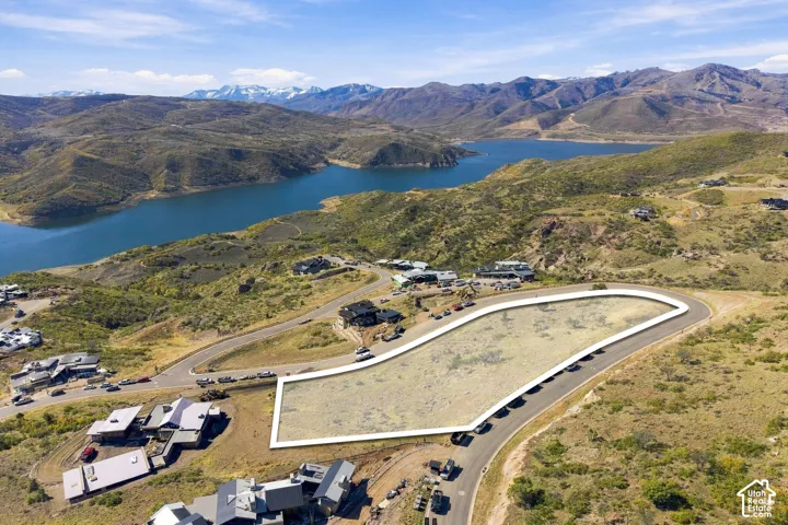 Vacant lot with significant acreage, paved road access, mountain backdrop, and water proximity