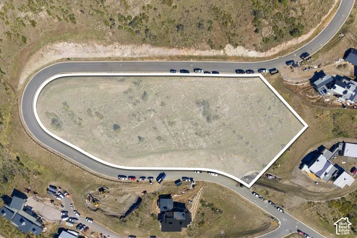 Expansive corner lot with topographical variation, bounded by paved roads, offering significant buildable acreage