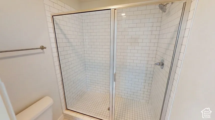 Walk-in shower featuring white subway tile walls, a tiled base, and a glass-paneled enclosure with a silver-finish shower head and mixer