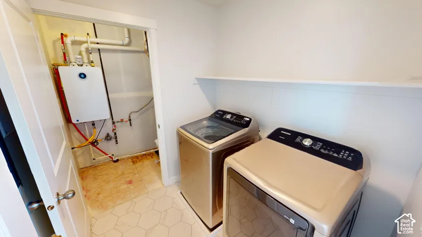 Dedicated laundry area featuring hexagonal floor tile, a wall-mounted shelf, and an integrated tankless water heater