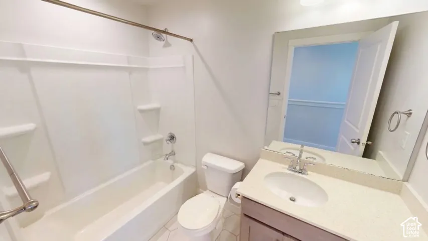 Bathroom featuring a white tub-shower combination with integrated shelving, a light-toned vanity with an oval undermount sink, and a large wall-mounted mirror