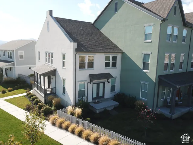 Multi-story residence featuring a combination of stucco and lap siding, a pitched shingle roof, a covered front porch with a wood-rail perimeter, and a picket-style fence