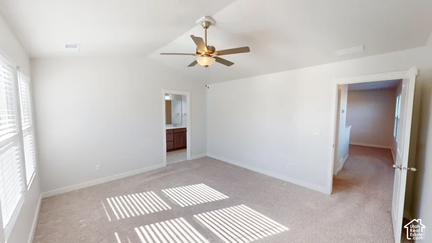 Vaulted ceilings featuring a brushed nickel ceiling fan, neutral carpeting, and multi-pane windows